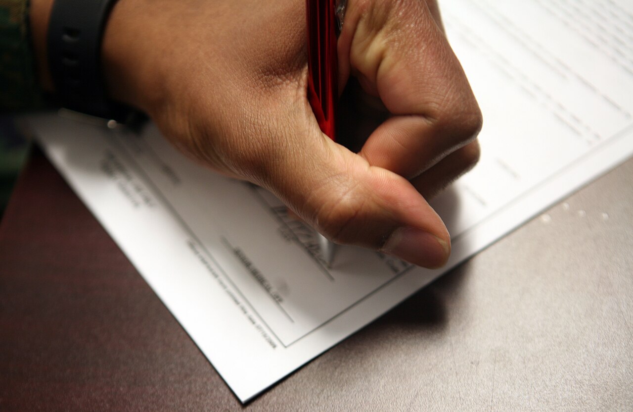 Una mano escribe sobre un documento